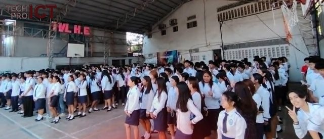 Senior high students in school uniform stand in rows inside the covered court.